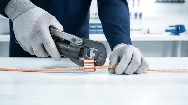 Hands crimping a copper C-tap grounding connector with a hydraulic crimper | Conversions Tech