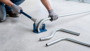 Electrician bending EMT conduit with a hand bender beside finished 90 and offset bends | Conversions Tech
